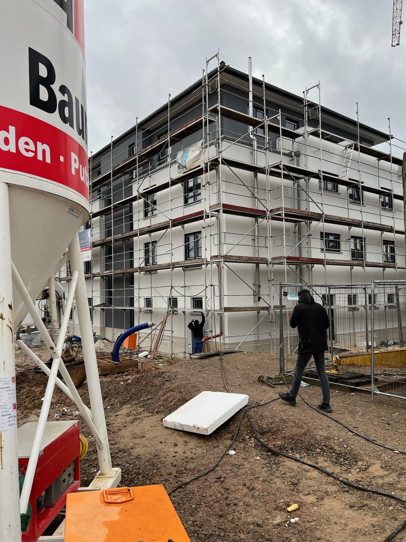 Rohbau eines Wohnhauses mit Gerüst und Silo auf der Baustelle