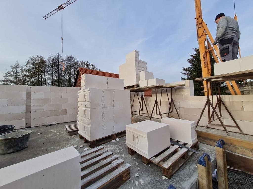 Kalksandstein-Mauerwerk im Rohbau, daneben Steinpakete und Kran