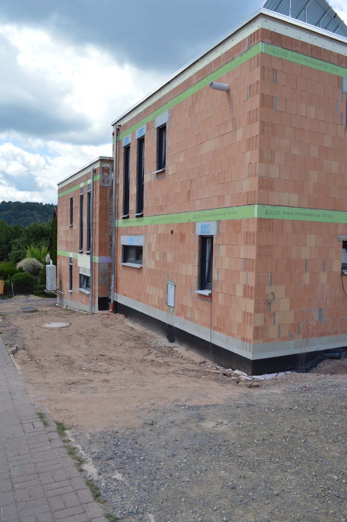 Gemauerter Ziegelrohbau eines Einfamilienhauses, von der Straße aus gesehen