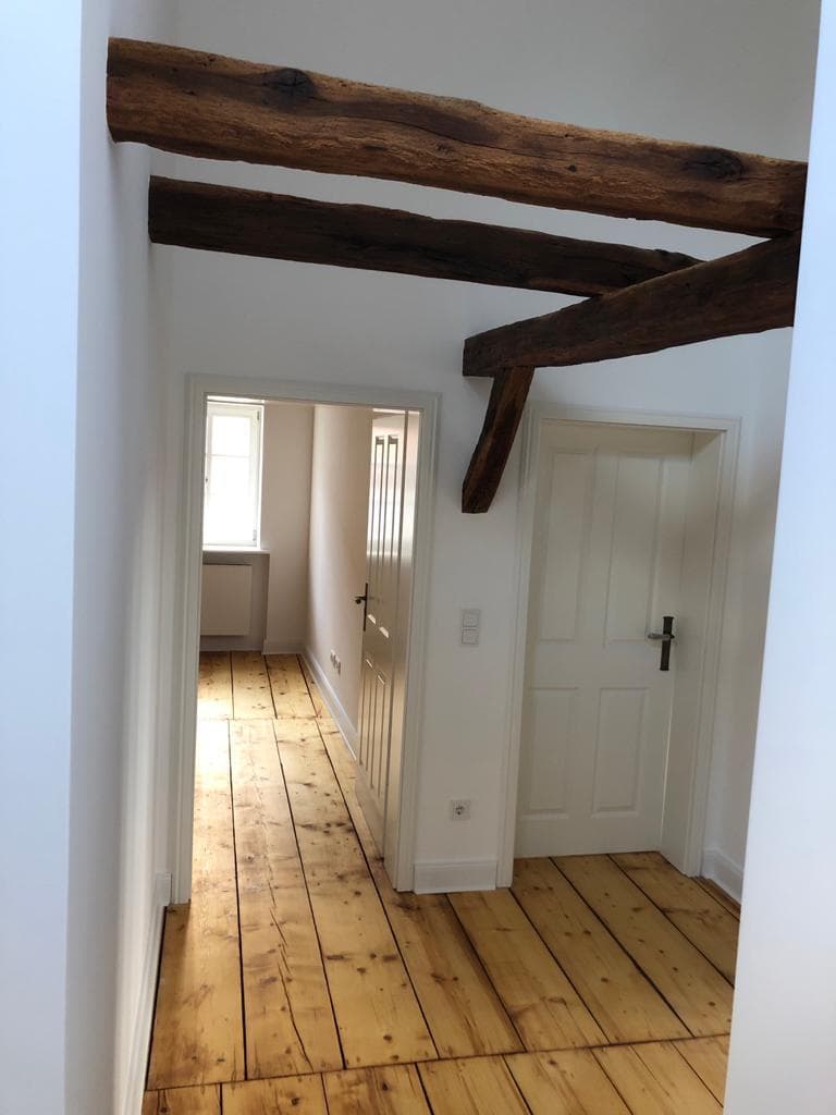 Sanierter Flur mit massiven Altholz-Deckenbalken und Dielenboden