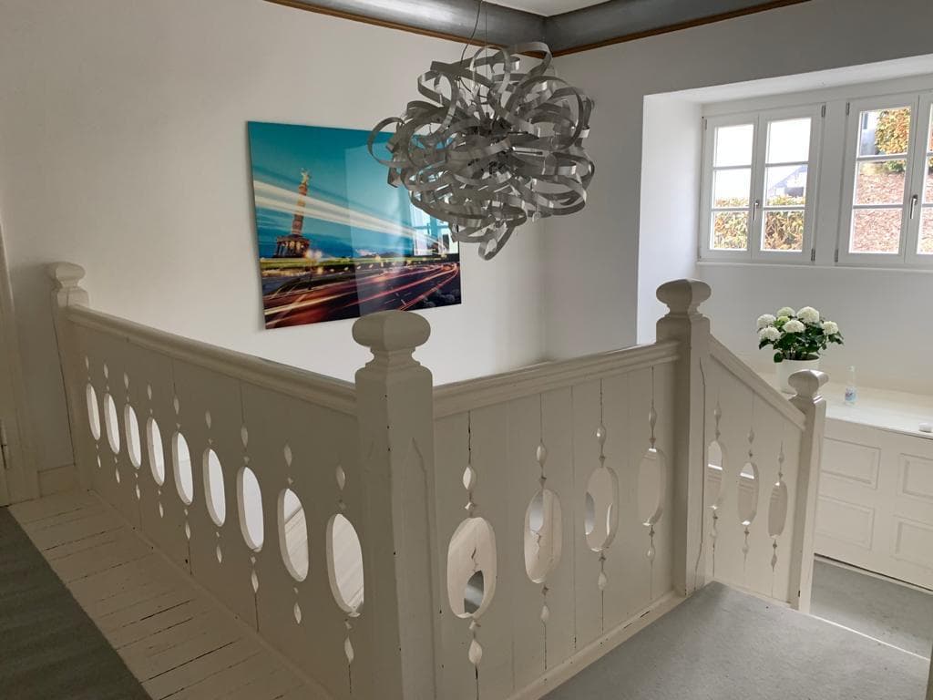 Helle Galerie mit fein geschnitztem Holzgeländer und modernem Lüster